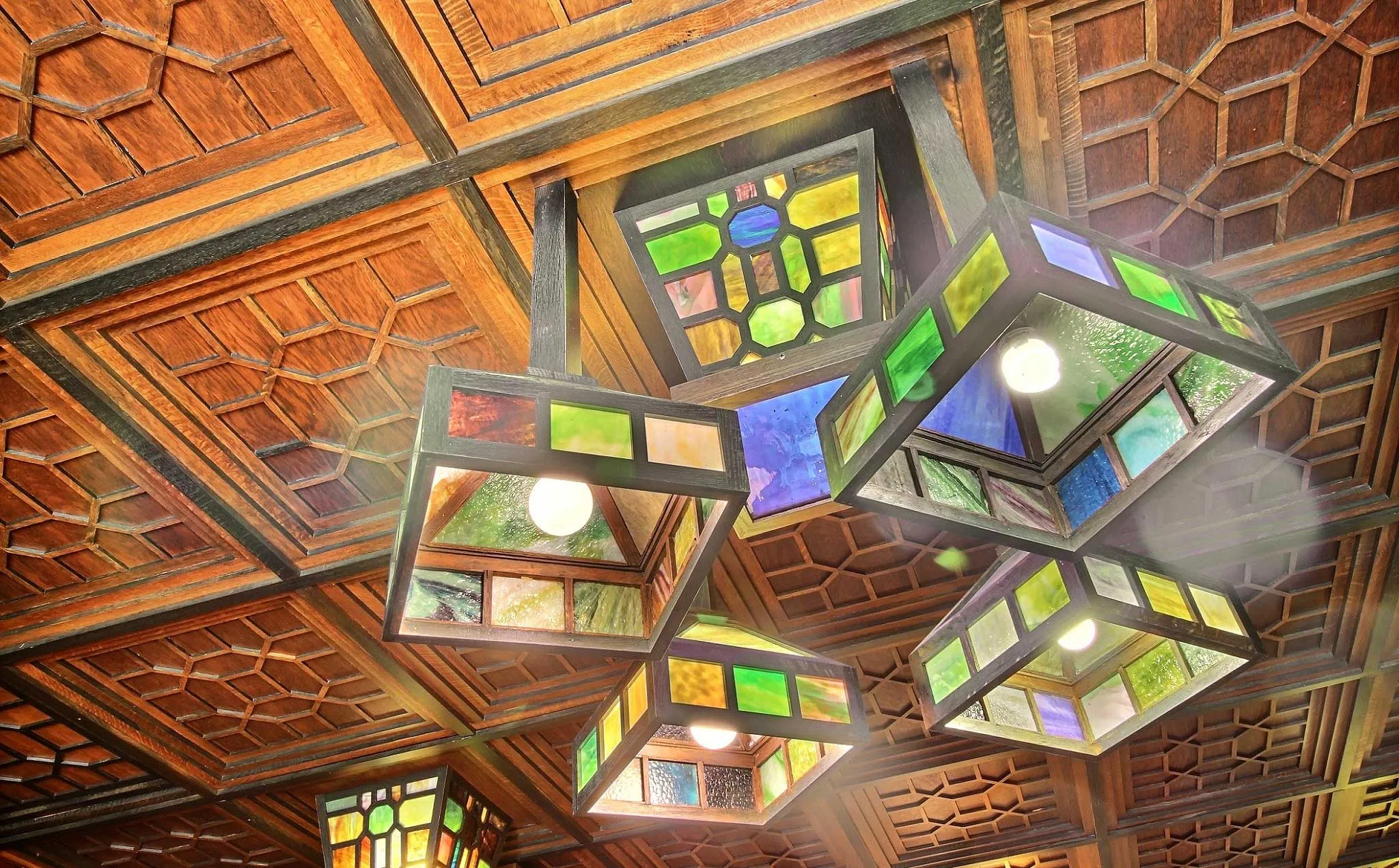 Stained glass lanterns hanging from a carved wooden ceiling